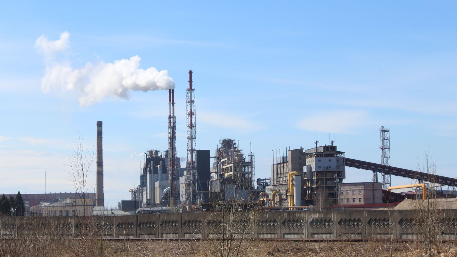 Industriële fabriek met uitstoot onder een blauwe lucht